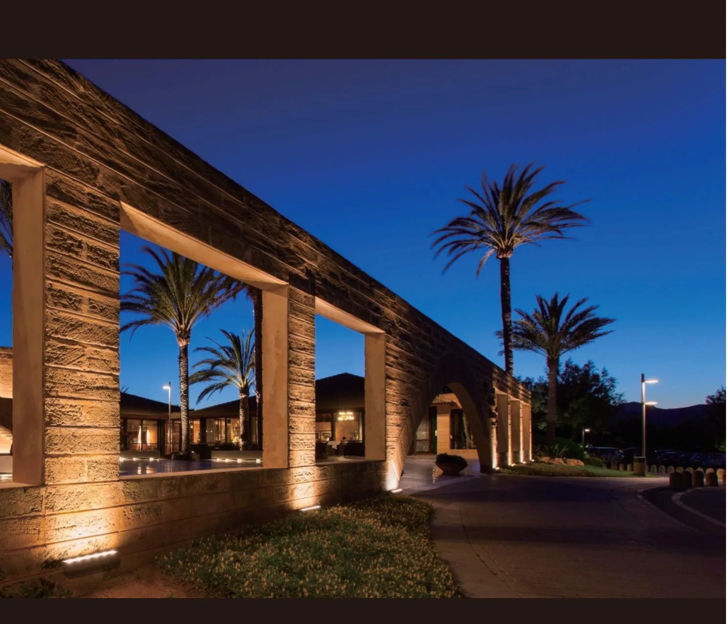Stone colonnade at dusk, each column uplit from an in-ground fixture