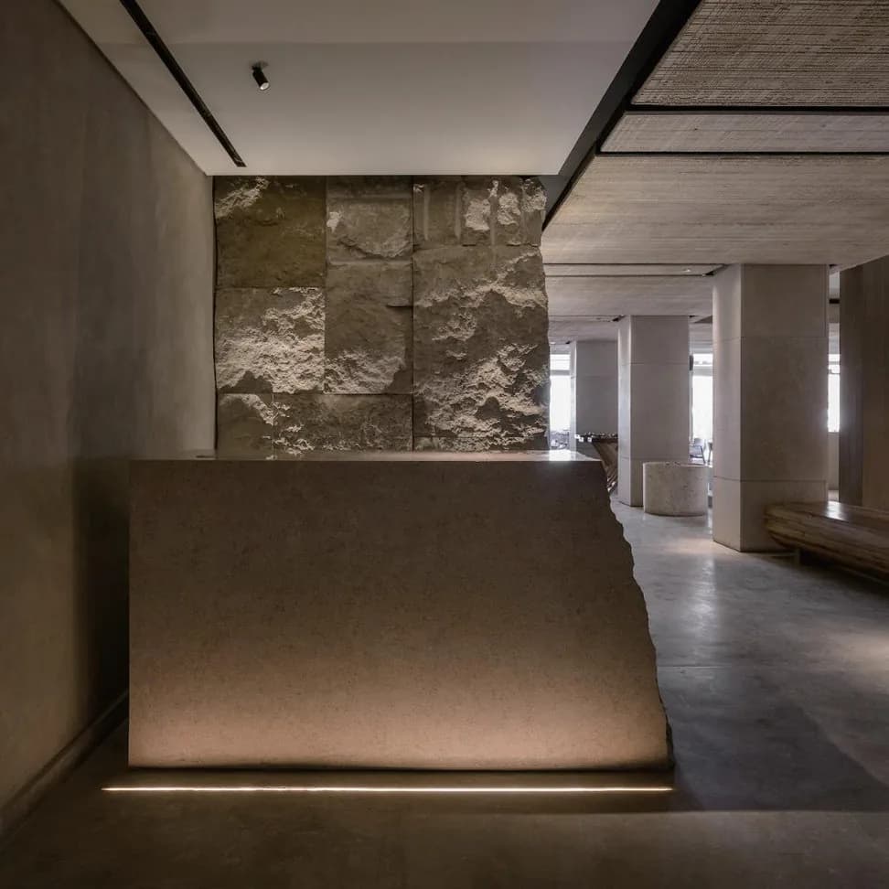 Recessed spotlights grazing a rough stone wall and a stone counter