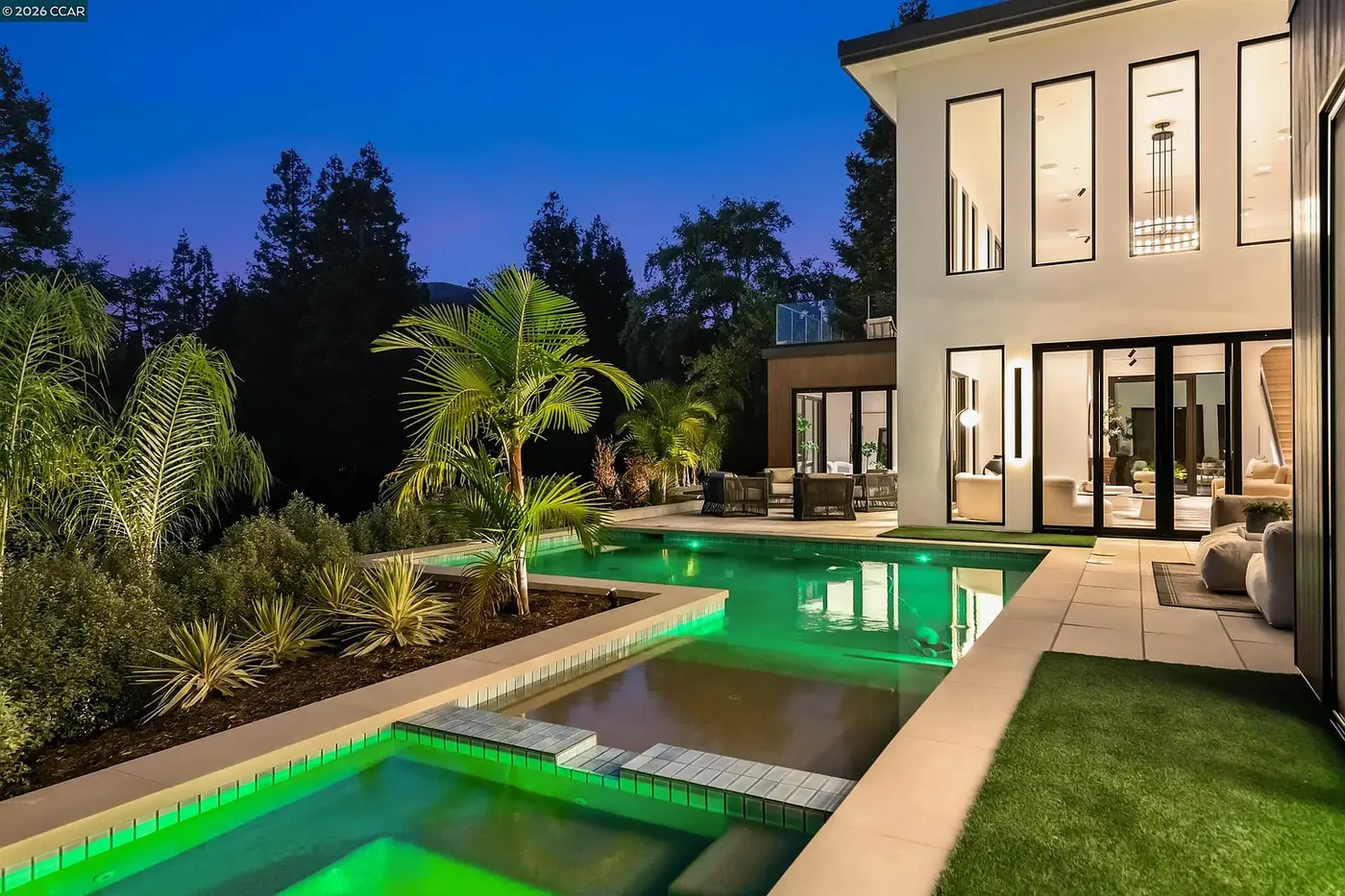 Pool and planting at dusk against the lit elevation