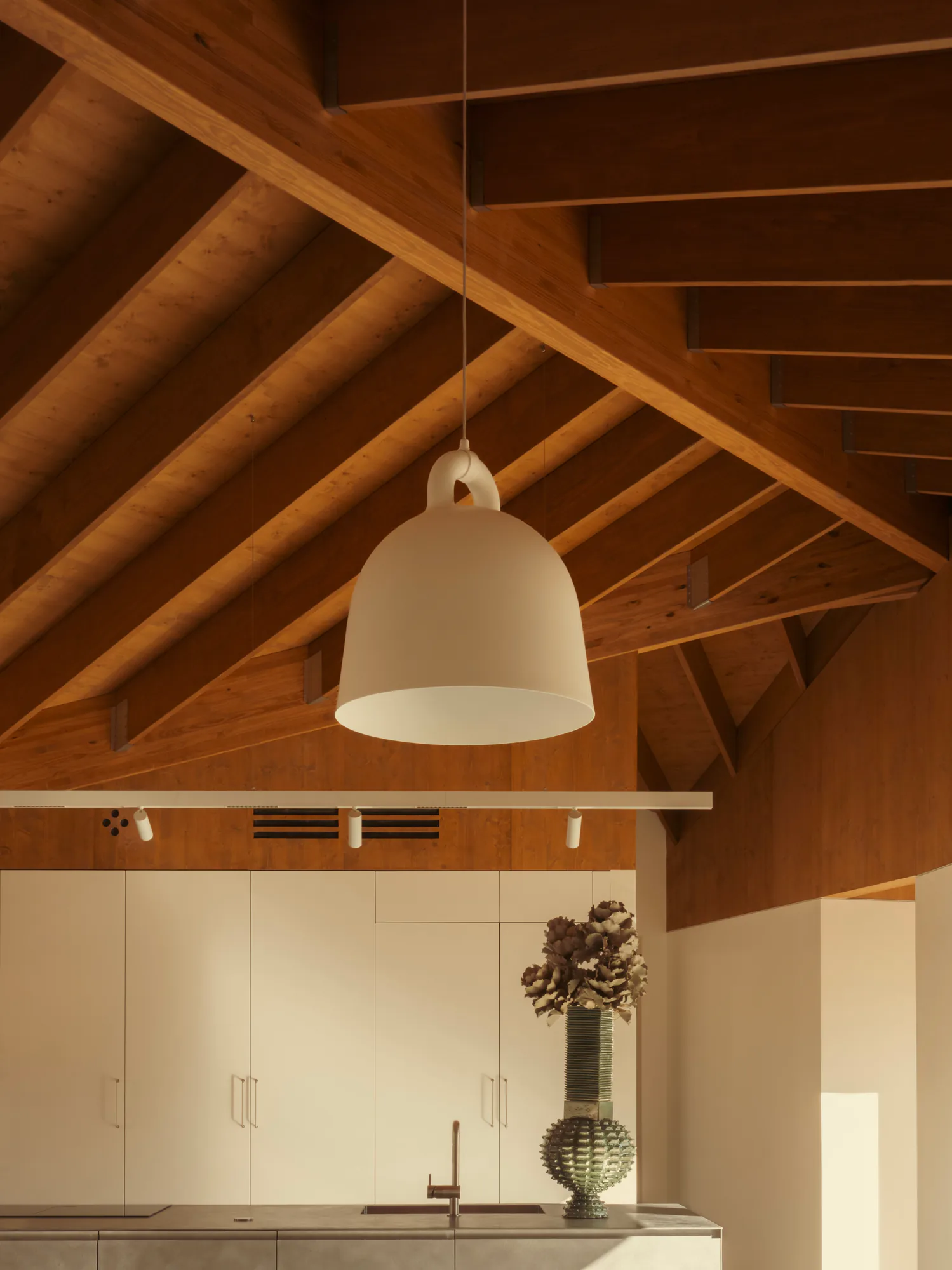 Bell pendant hanging from the rafters, track heads on the beam below it