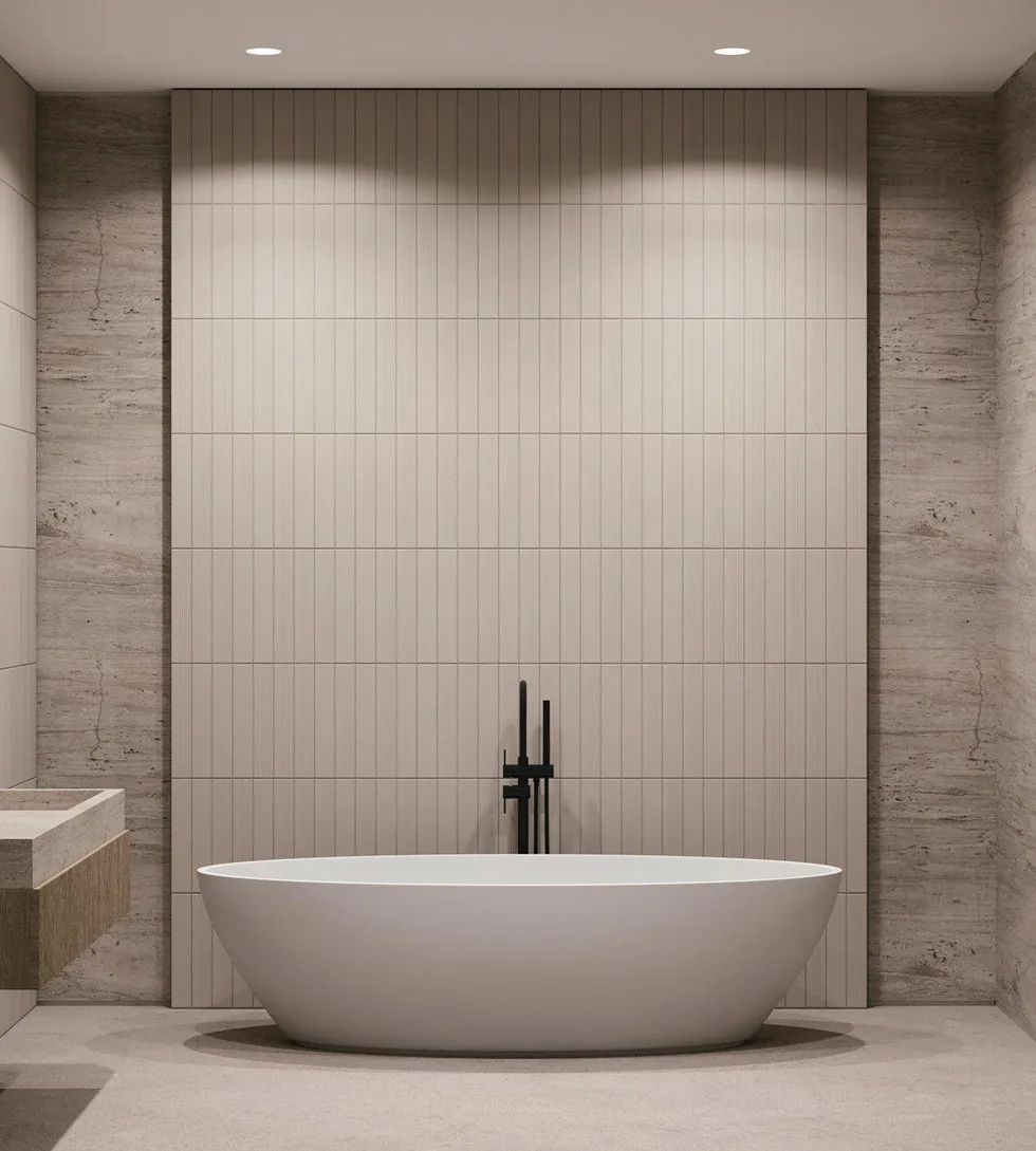 Bathroom with a freestanding tub, the stone wall grazed by recessed downlights