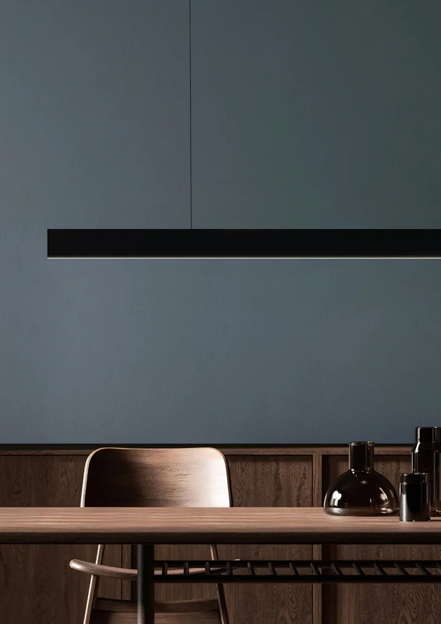 Black linear pendant suspended over a wooden dining table