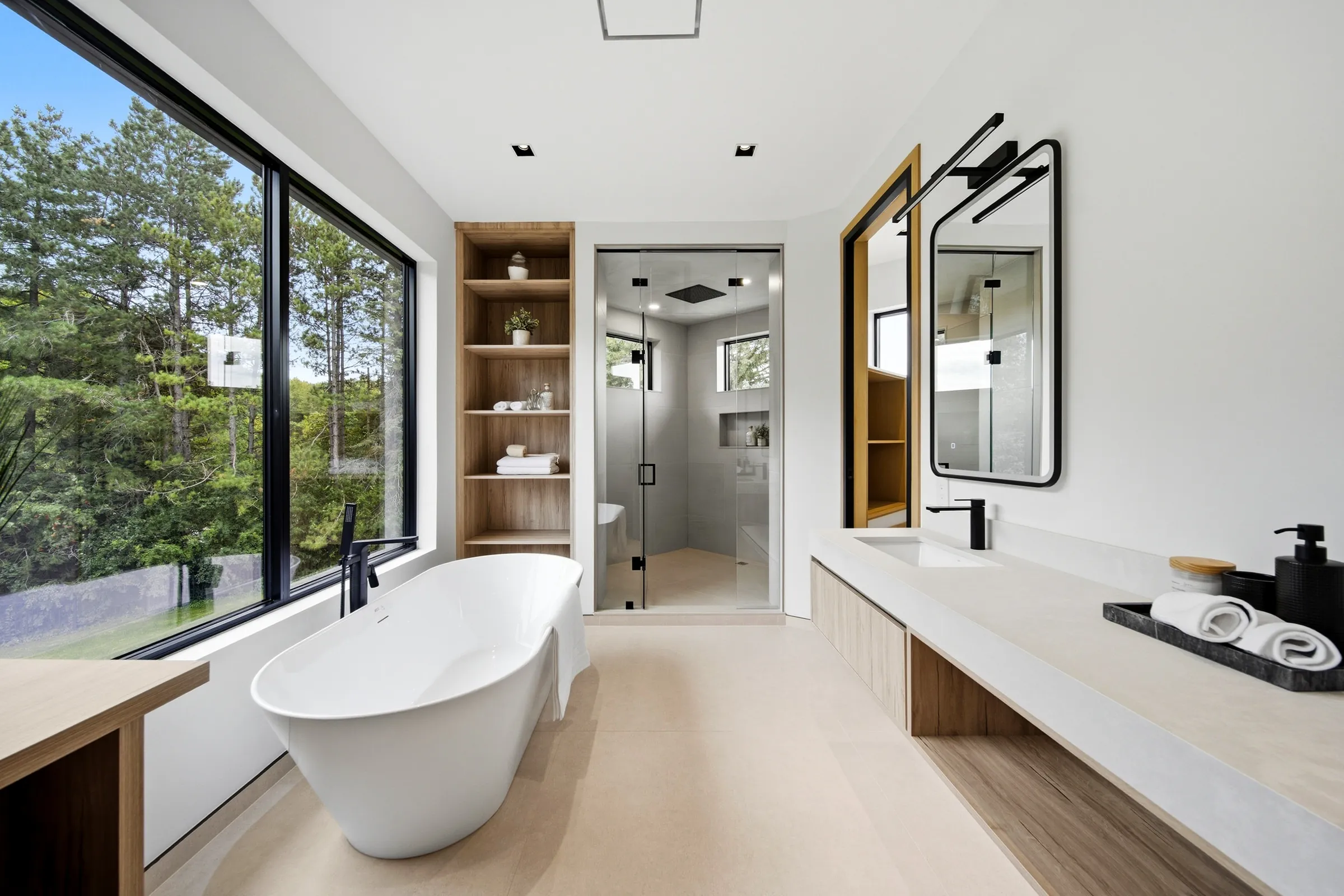 Black linear wall lights mounted over the mirrors of a primary bath vanity