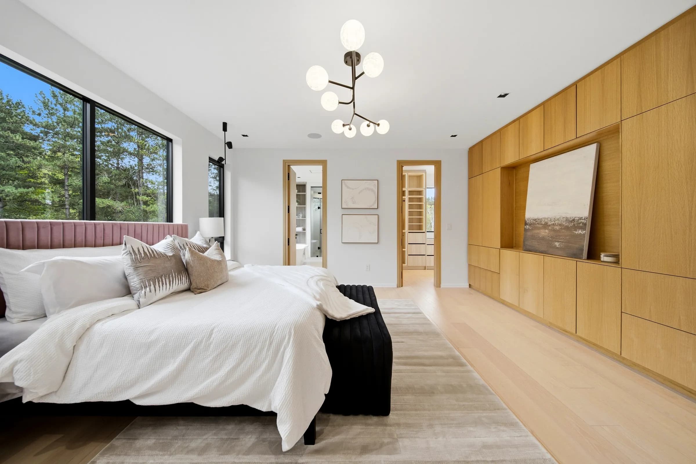 Primary bedroom lit by a branching fixture with glass globe shades