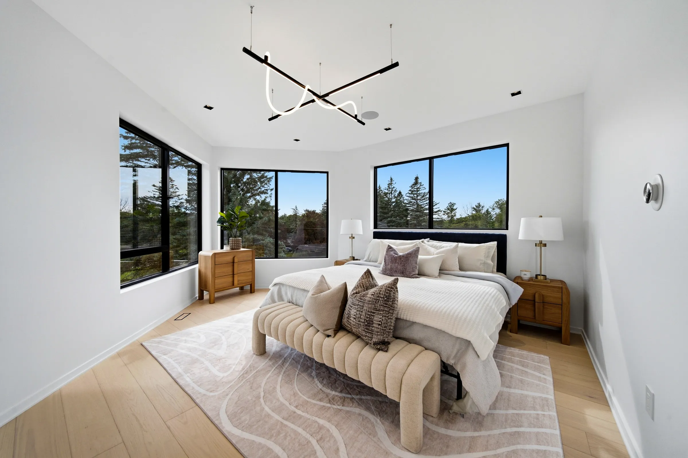 Primary bedroom with the linear pendant and neon loop over the bed, windows on two sides