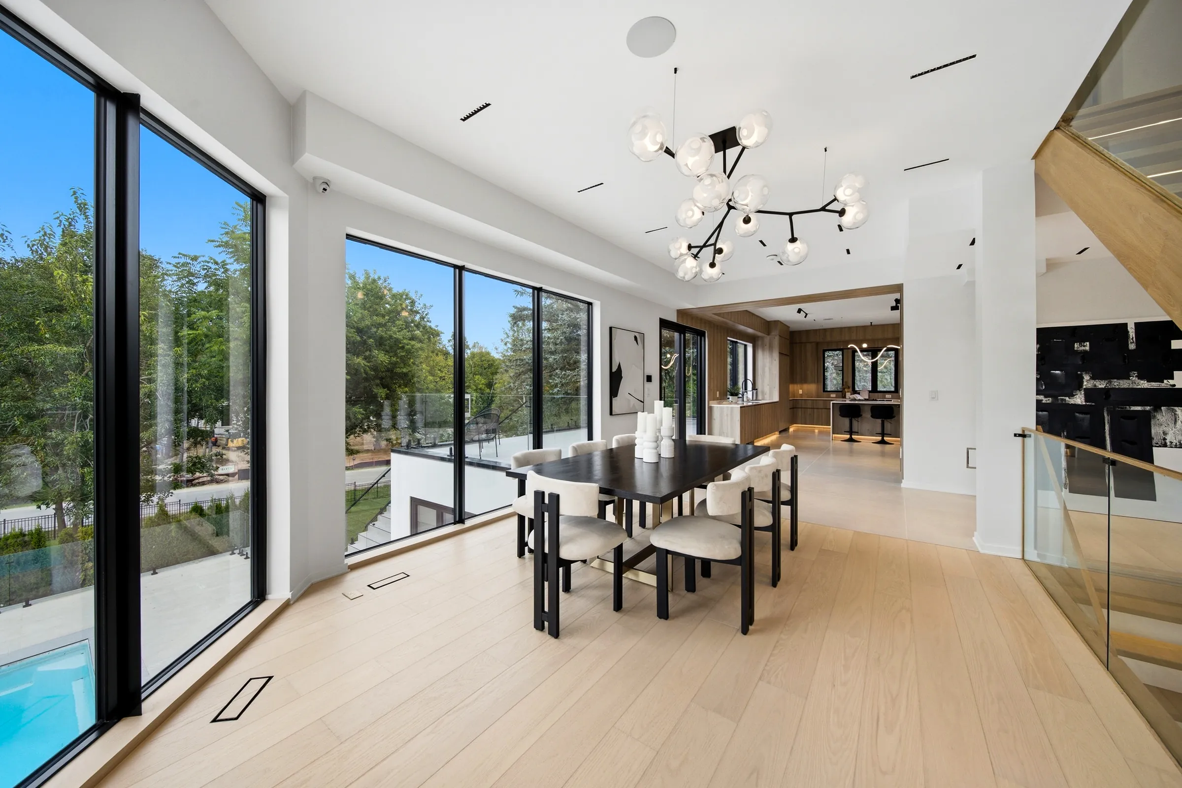 Dining table under the branch chandelier, floor to ceiling glazing on two sides