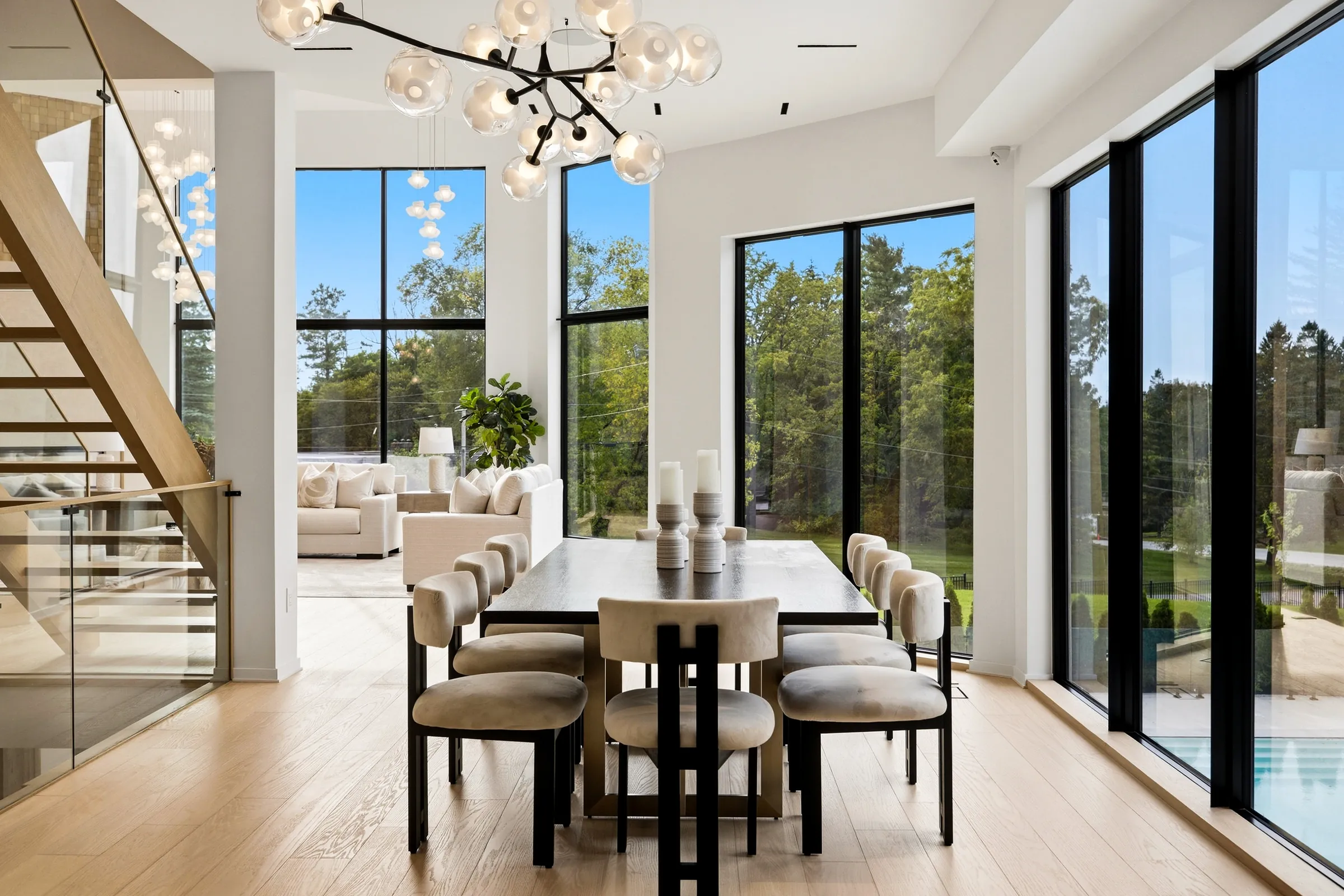 Dining room from the stair, branch chandelier over the table and the pool visible through the glazing