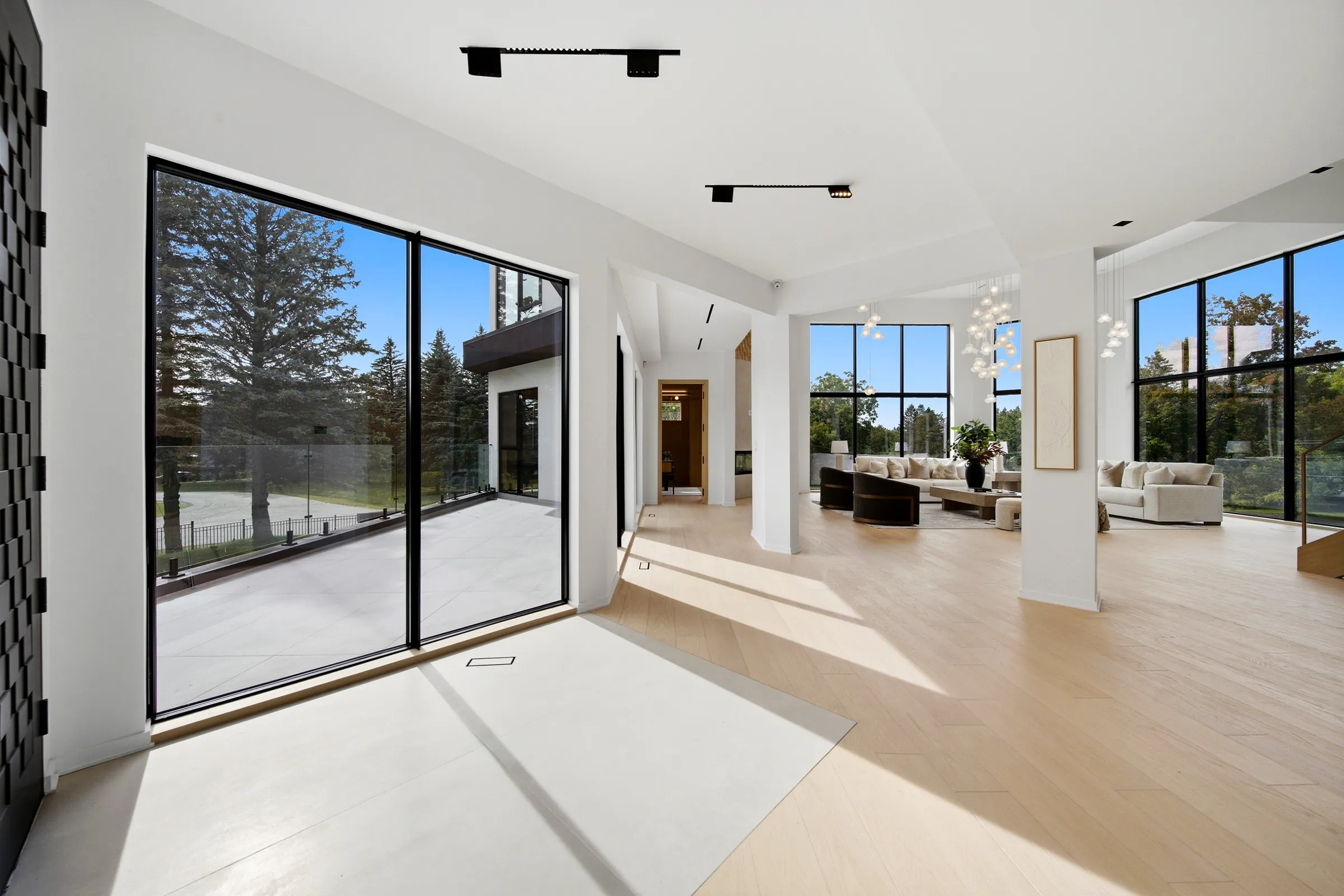 Entry gallery with sliding doors to the terrace, track spots overhead and the great room beyond