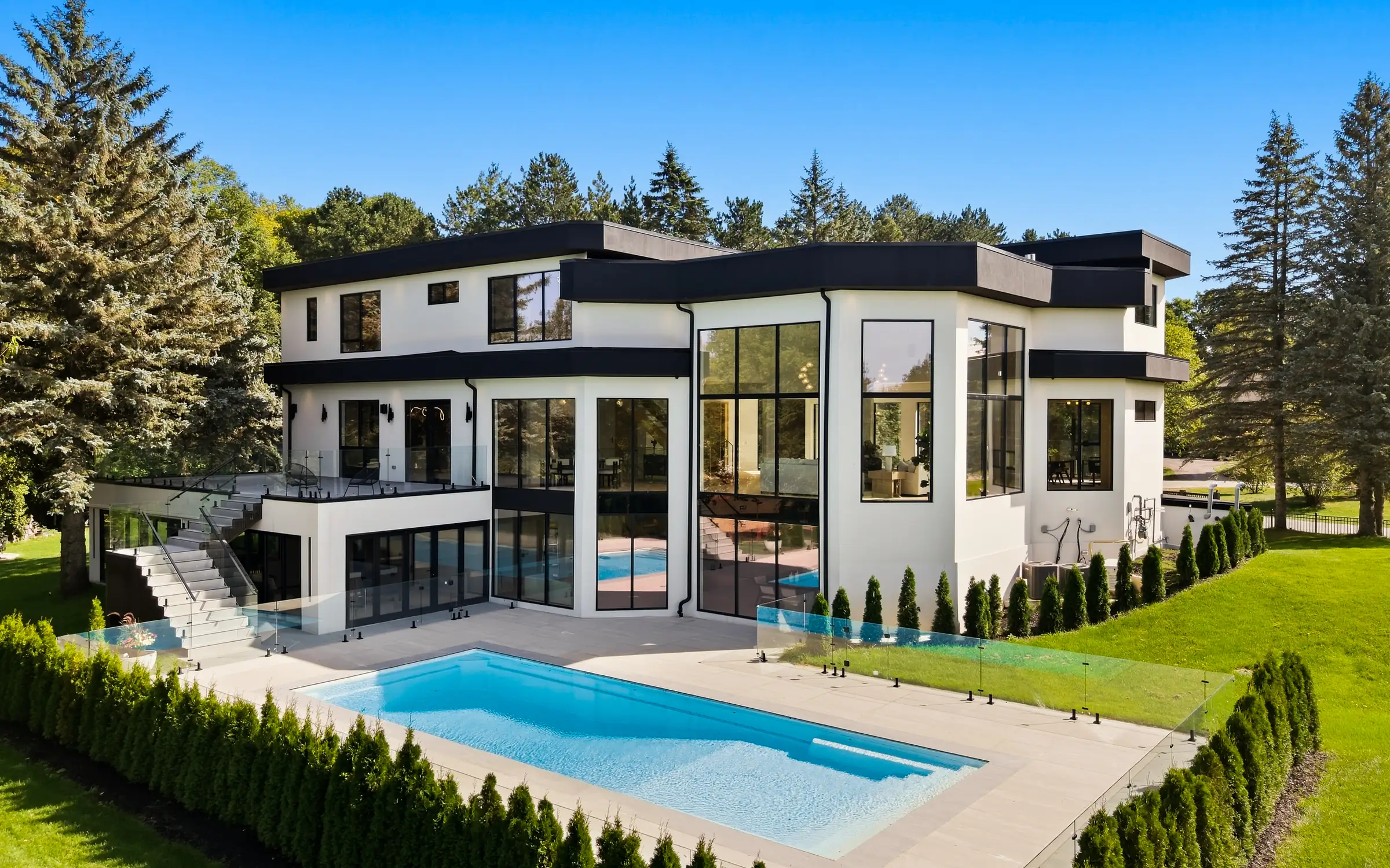 Rear elevation in daylight with the pool, exterior stair and lower level walkout