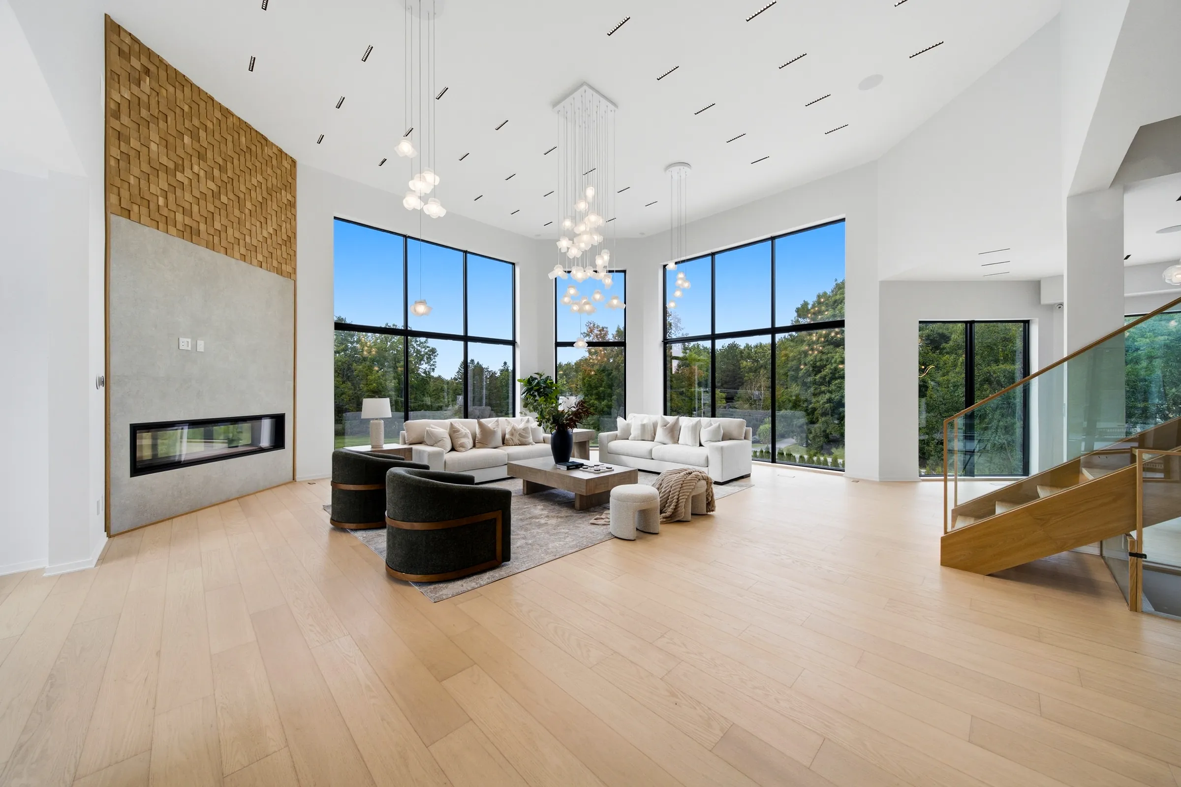 Great room in daylight, globe pendant cluster hanging from the double height ceiling beside the open stair