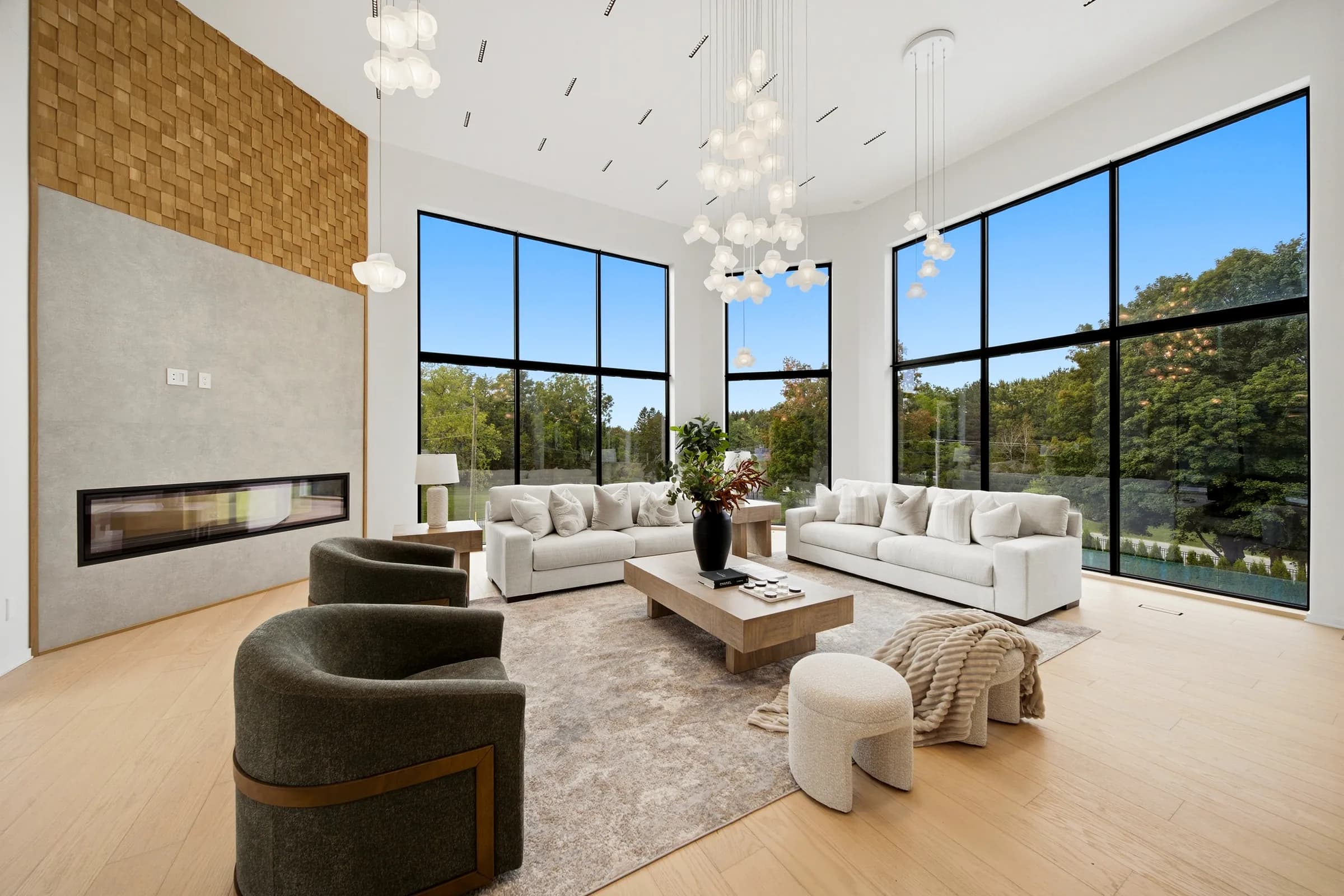 Great room seating under the pendant cluster, linear ceiling slots and the fireplace wall in daylight