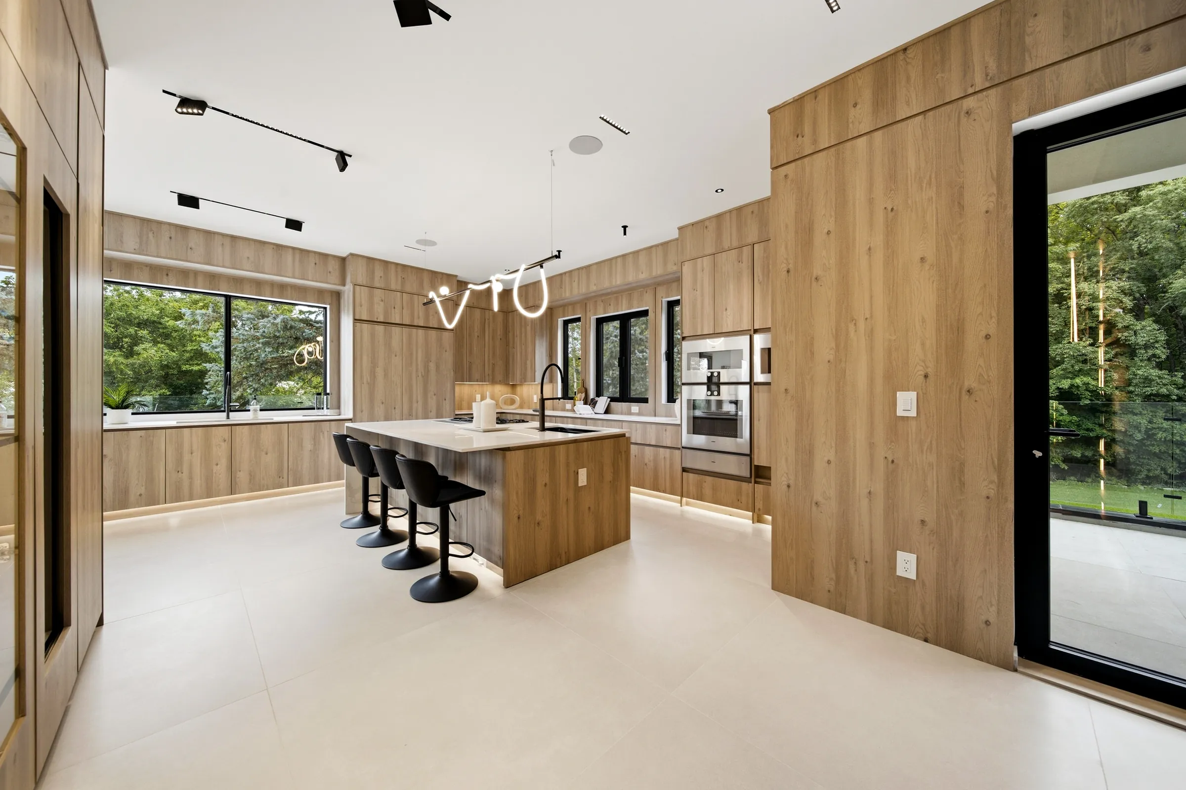 Kitchen from the doorway, looping pendant over the island and ceiling track heads along the oak ceiling
