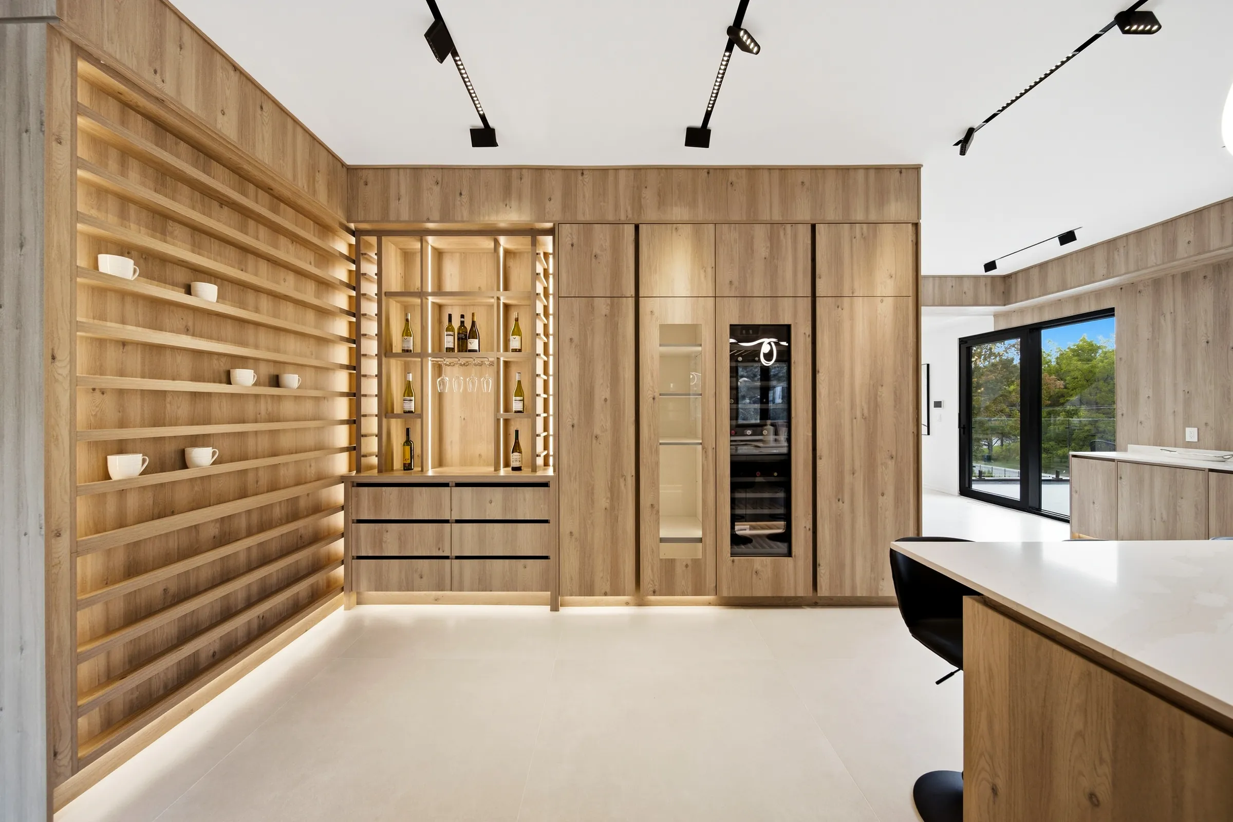 Backlit oak slat wall and bar shelving with integrated shelf lighting beside the kitchen