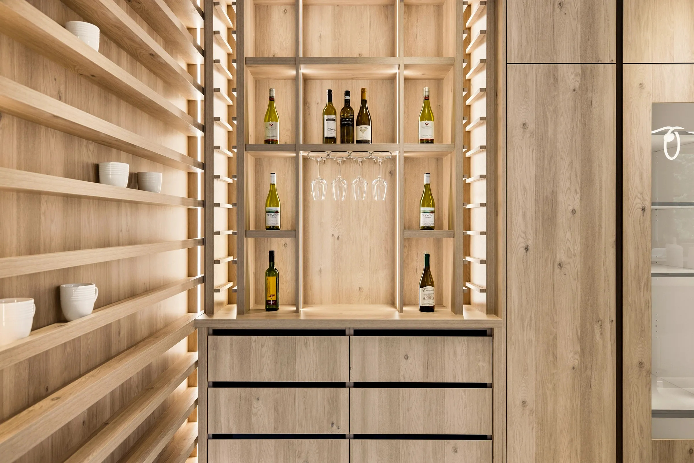 Detail of the bar shelving with light strips behind the oak slats and bottles on the lit shelves