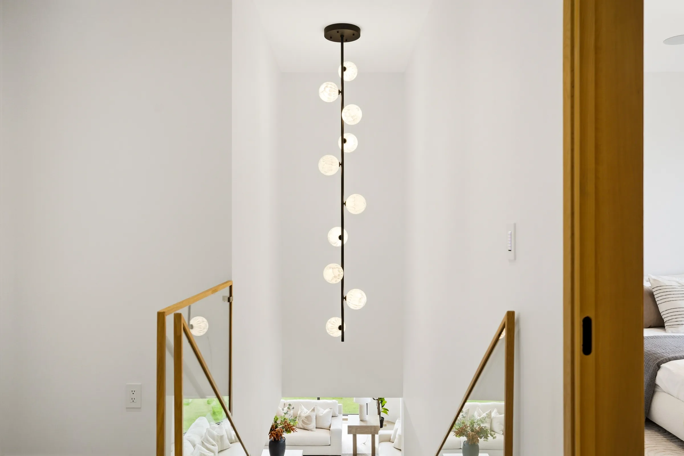 Vertical globe pendant hanging through the stairwell over the glass balustrade
