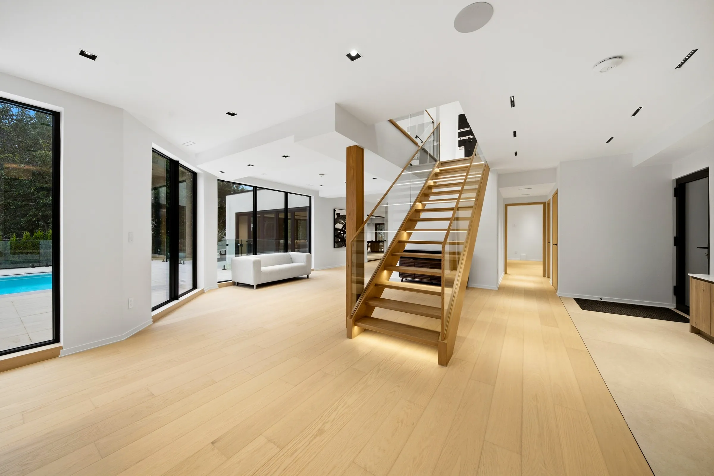 Lower level with the open oak stair, recessed linear ceiling slots and glazing to the pool