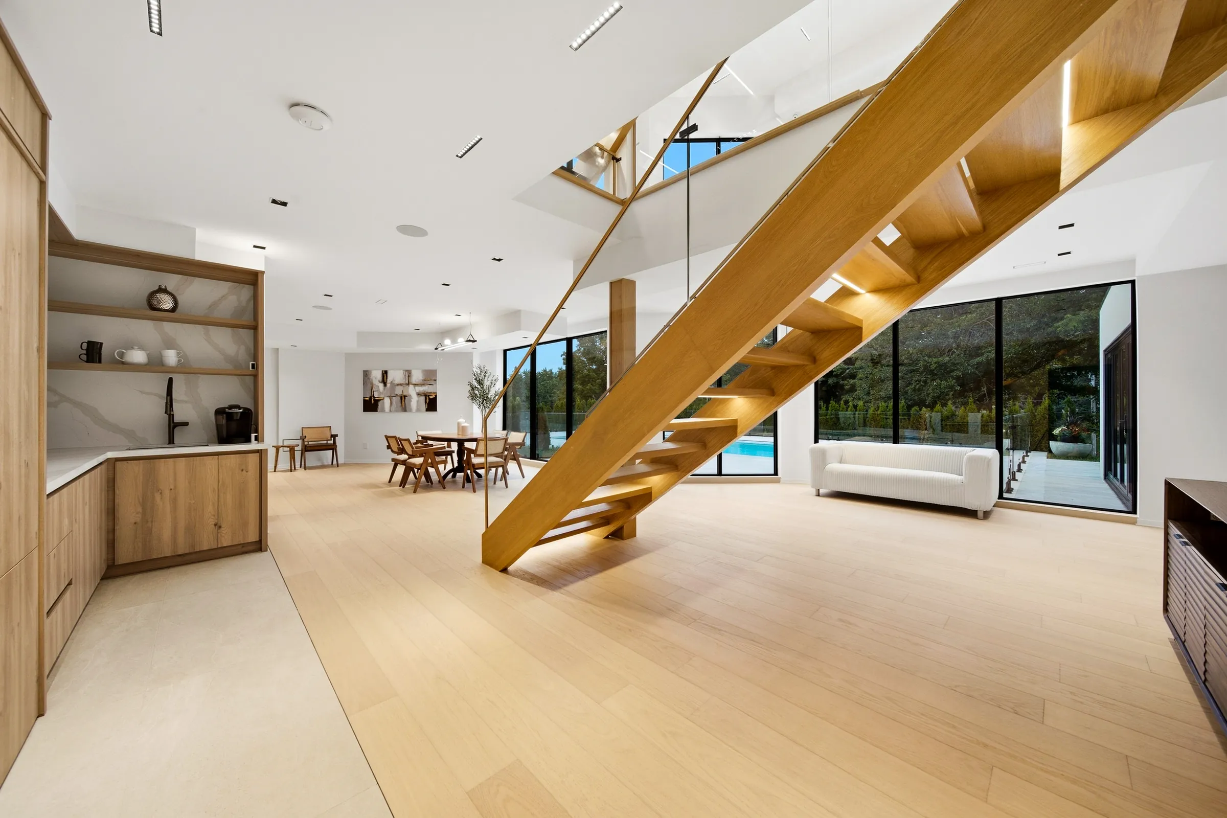 Underside of the oak stair from the lower level, linear ceiling lights and the walkout glazing