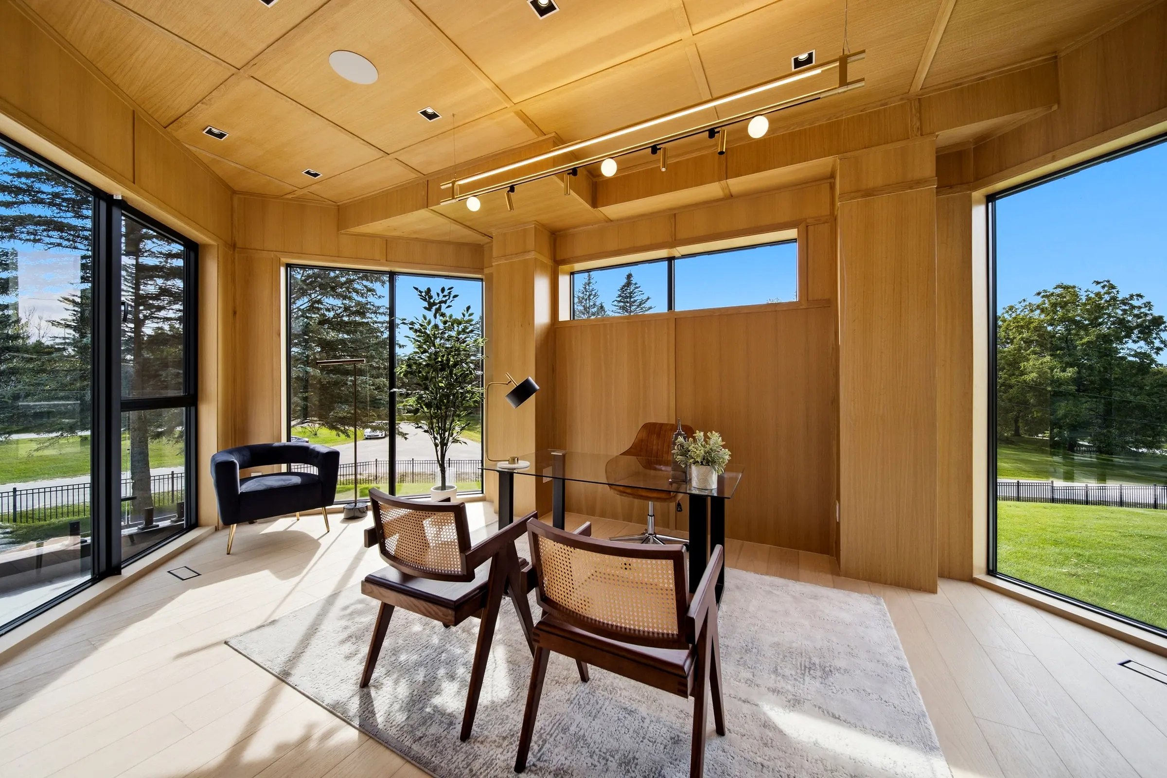 Oak clad study with a track of spotlights across the ceiling and glazing on two sides