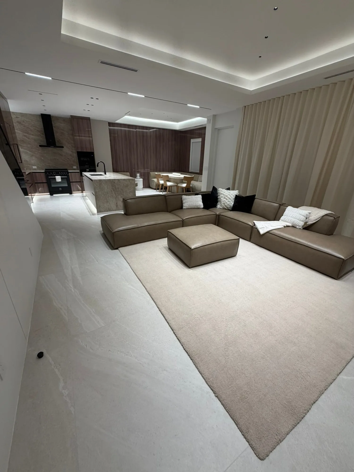 Living room under a stepped cove ceiling, kitchen and dining beyond