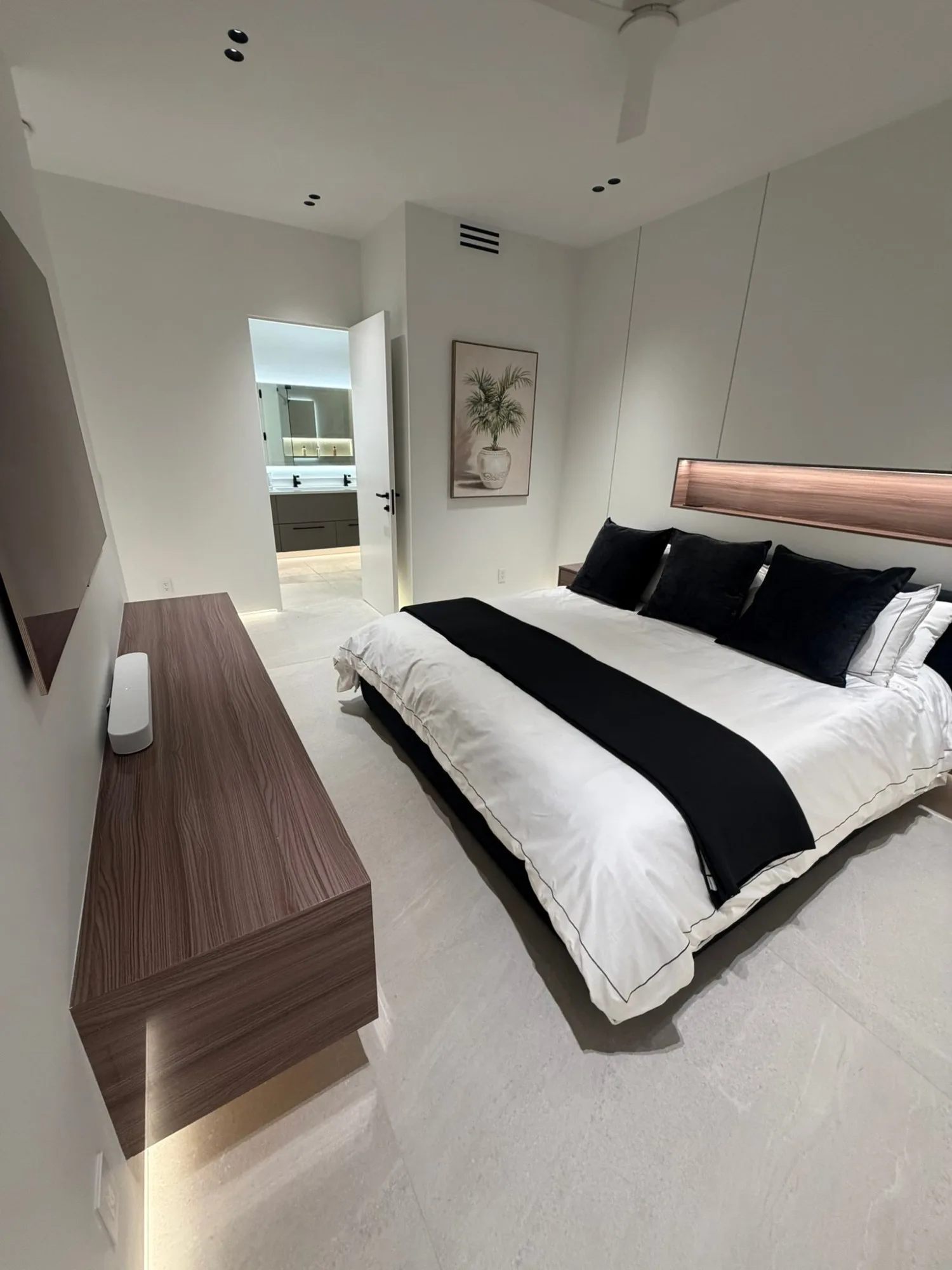 Primary bedroom with a floating media console and the ensuite beyond