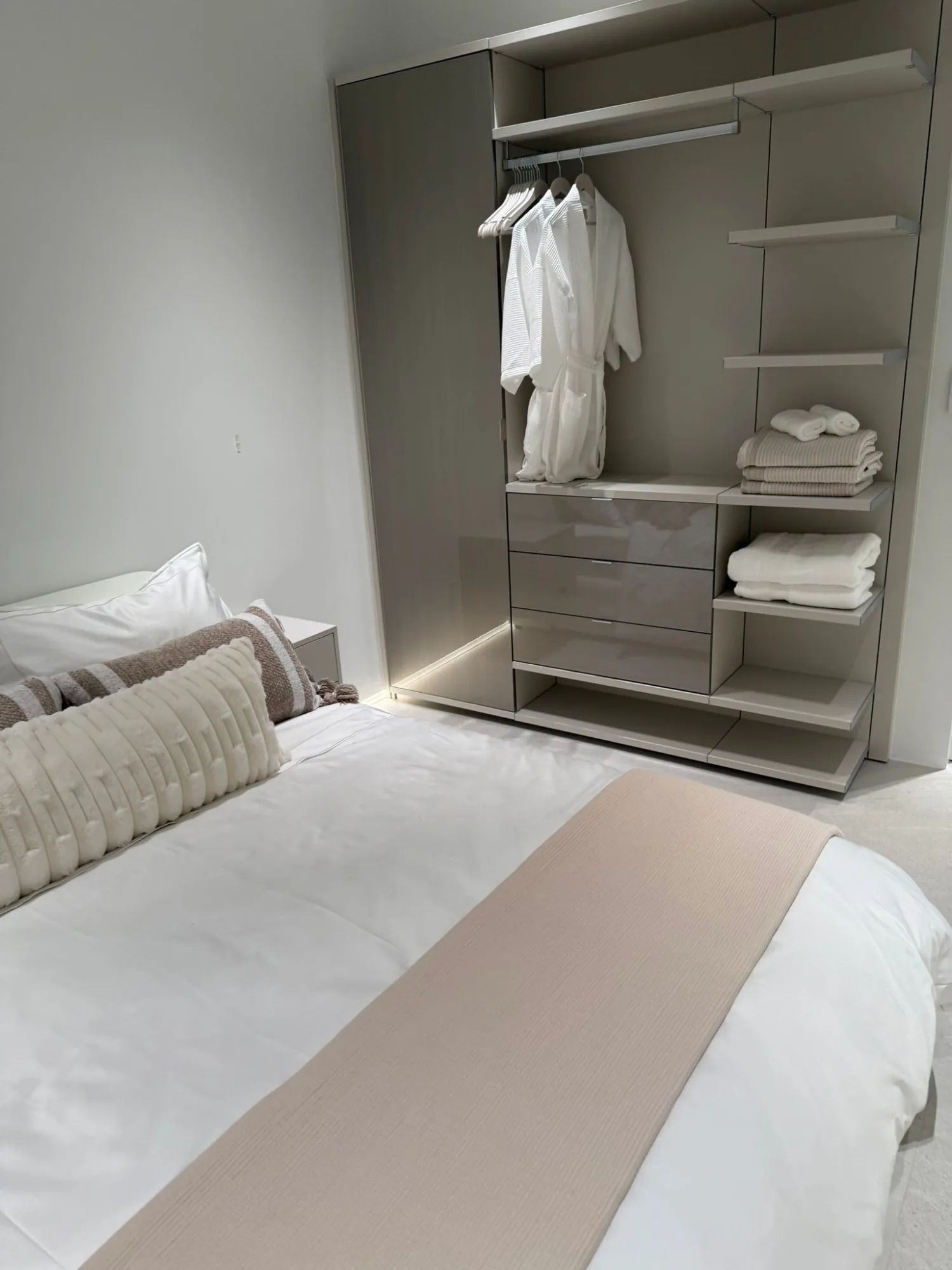 Open wardrobe with robes and towels over a lit base