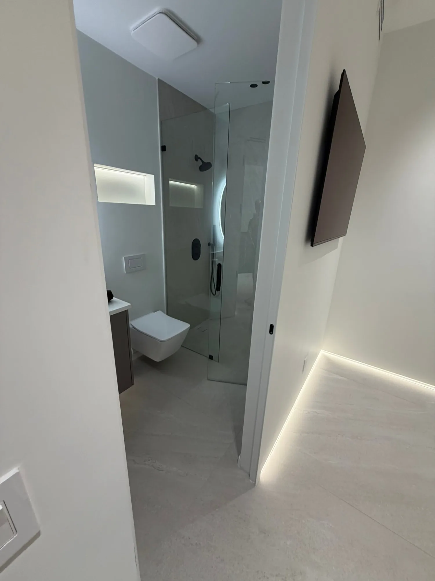 Guest bath seen from the hall, floor washed by a low tape line