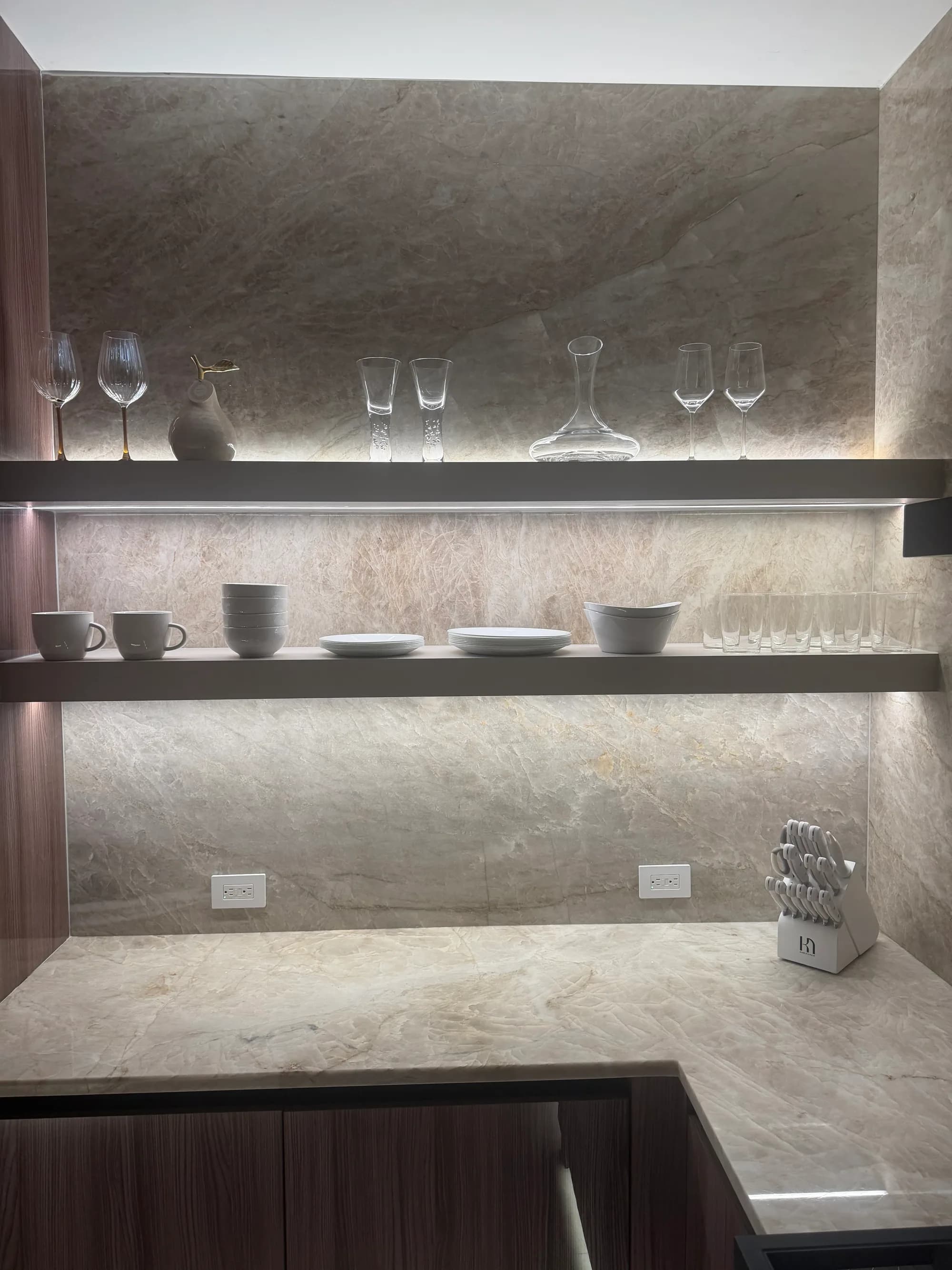 Floating stone shelves lit from beneath against a marble wall